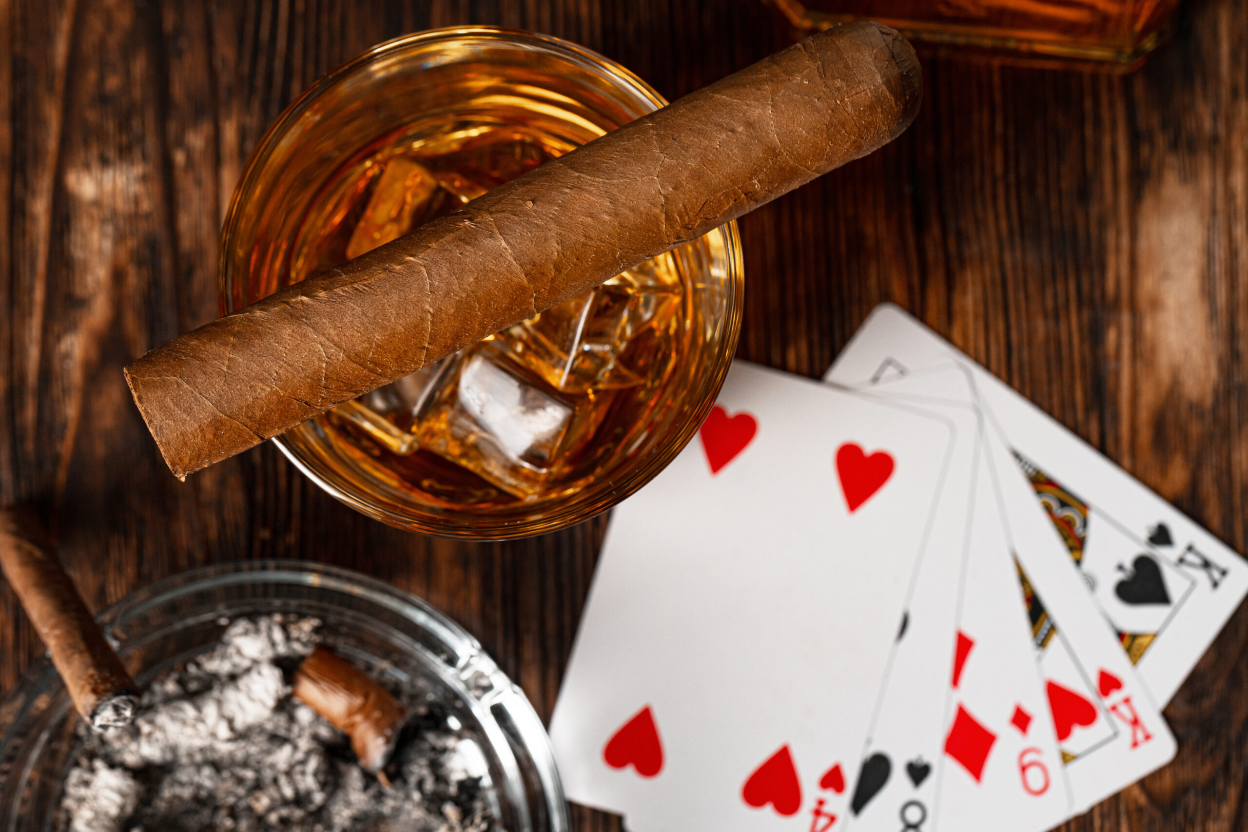 Playing poker with whiskey and cigars on table